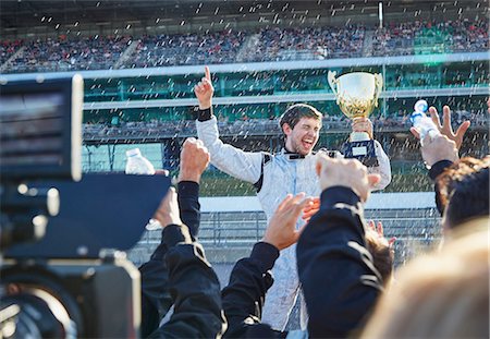 simsearch:6113-08927838,k - Formula one racing team spraying champagne on driver with trophy, celebrating victory on sports track Photographie de stock - Premium Libres de Droits, Code: 6113-08927851