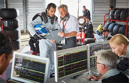 extreme sports team - Manager and formula one driver discussing telemetry diagnostics in repair garage Stock Photo - Premium Royalty-Free, Code: 6113-08927878