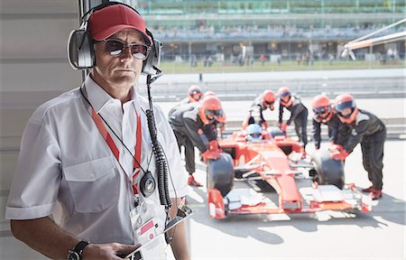 simsearch:6105-07744436,k - Portrait serious manager with formula one race car and pit crew in background Stock Photo - Premium Royalty-Free, Code: 6113-08927825
