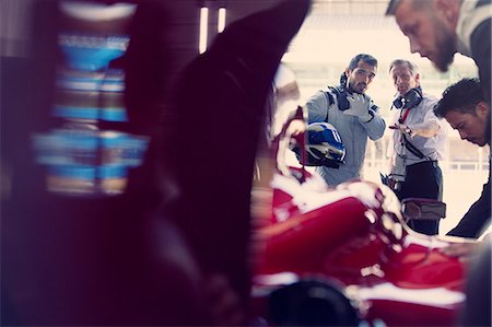 simsearch:6113-08927954,k - Manager and formula one race car driver talking in repair garage Stock Photo - Premium Royalty-Free, Code: 6113-08927957