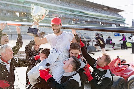 simsearch:6113-06720836,k - Formula one racing team carrying driver with trophy on shoulders, celebrating victory on sports track Foto de stock - Sin royalties Premium, Código: 6113-08927962