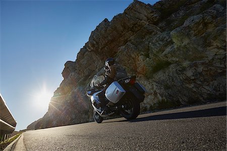 simsearch:6113-07589489,k - Couple riding motorcycle on sunny road along craggy cliff Stock Photo - Premium Royalty-Free, Code: 6113-08927969