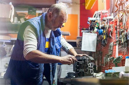 Senior male motorcycle mechanic fixing engine part  in workshop Stock Photo - Premium Royalty-Free, Code: 6113-08927981