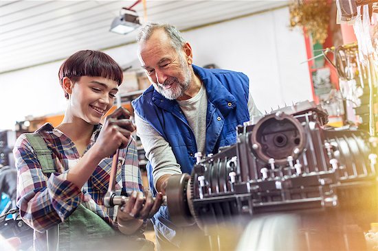 Male and female motorcycle mechanics repairing engine in workshop Stock Photo - Premium Royalty-Free, Image code: 6113-08927987