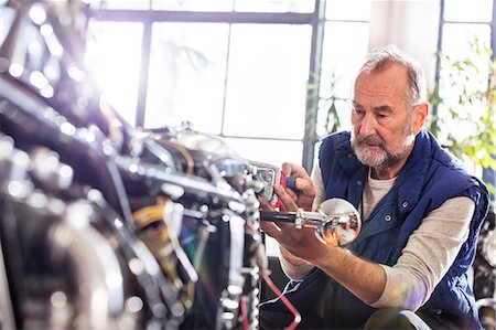 seniors motorcycle - Senior male motorcycle mechanic fixing motorcycle in workshop Stock Photo - Premium Royalty-Free, Code: 6113-08927984