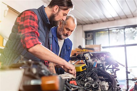 father son indoors - Motorcycle mechanics repairing motorcycle in workshop Stock Photo - Premium Royalty-Free, Code: 6113-08927990