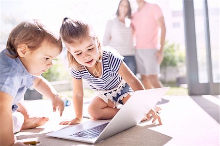 Brother and sister using laptop on sunny floor Photographie de stock - Premium Libres de Droits, Code: 6113-08928049