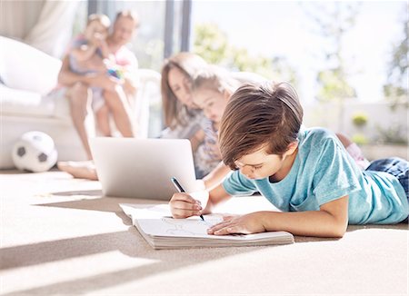 drawings of a girl and boy - Boy coloring in coloring book on sunny living room floor Stock Photo - Premium Royalty-Free, Code: 6113-08928055