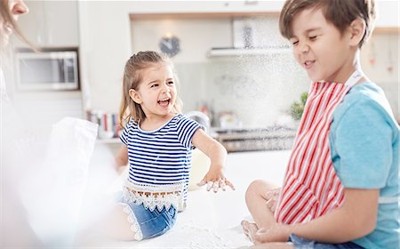 family playing in the kitchen - Sister throwing flower at brother, baking in kitchen Stock Photo - Premium Royalty-Free, Code: 6113-08928063