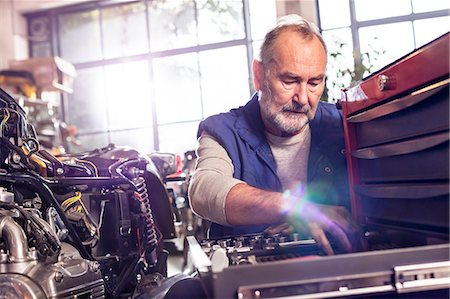 simsearch:6113-07565137,k - Senior male motorcycle mechanic retrieving tools in toolbox in workshop Stock Photo - Premium Royalty-Free, Code: 6113-08928004