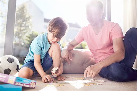 people holding puzzle pieces - Father and son assembling jigsaw pieces on floor Stock Photo - Premium Royalty-Free, Code: 6113-08928021