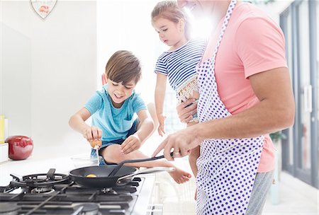 simsearch:6108-06167545,k - Father cooking breakfast at stove with daughter and son Foto de stock - Sin royalties Premium, Código: 6113-08928036