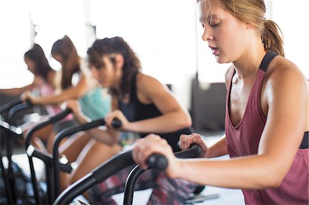 simsearch:649-05950199,k - Young woman using elliptical bike in exercise class Stock Photo - Premium Royalty-Free, Code: 6113-09058258