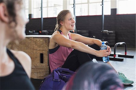 female sitting crate - Smiling young woman resting and drinking water post workout in gym Stock Photo - Premium Royalty-Free, Code: 6113-09058282