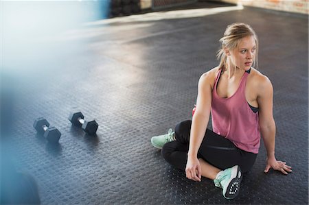 Young woman stretching, twisting in gym next to dumbbells Foto de stock - Sin royalties Premium, Código: 6113-09058289