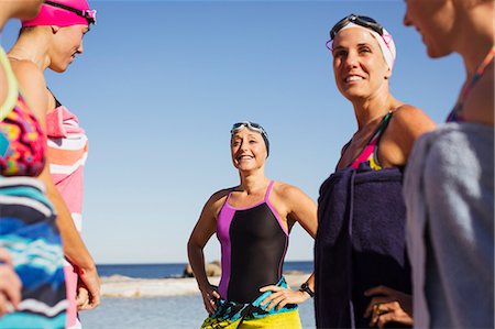 simsearch:6113-09058359,k - Smiling female open water swimmers wrapped din towels on sunny beach Foto de stock - Sin royalties Premium, Código: 6113-09058379