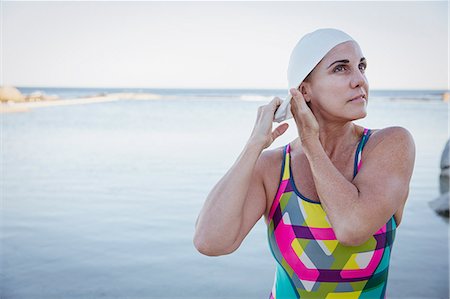 simsearch:6113-09058358,k - Female open water swimmer adjusting swimming cap at ocean Stock Photo - Premium Royalty-Free, Code: 6113-09058393