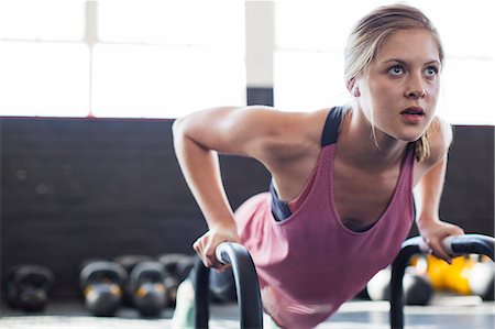 simsearch:649-03418201,k - Portrait determined, focused young woman doing push-ups with equipment in gym Photographie de stock - Premium Libres de Droits, Code: 6113-09058304