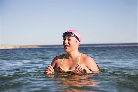 simsearch:6113-09058359,k - Smiling female open water swimmer swimming in sunny ocean Foto de stock - Sin royalties Premium, Código: 6113-09058331