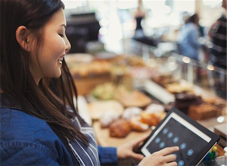 Smiling cashier using touch screen cash register in cafe Stock Photo - Premium Royalty-Free, Code: 6113-09058489