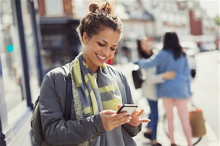 sent - Smiling young woman texting with cell phone on sunny urban street Stock Photo - Premium Royalty-Free, Code: 6113-09058494