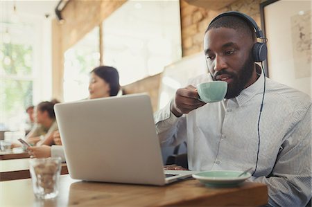 simsearch:6113-07542825,k - Man with headphones using laptop and drinking coffee in cafe Stock Photo - Premium Royalty-Free, Code: 6113-09058499