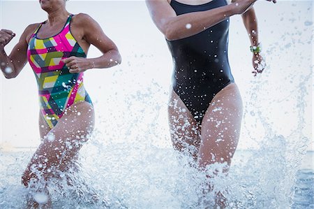 simsearch:649-08560912,k - Female open water swimmers running and splashing in ocean surf Stock Photo - Premium Royalty-Free, Code: 6113-09058405