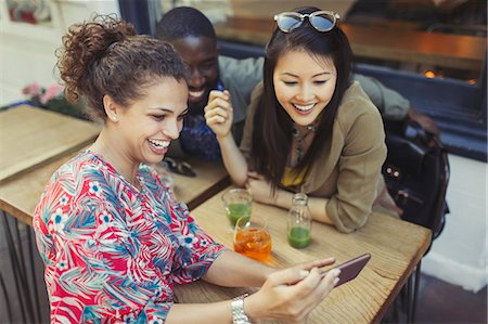 Young women friends using smart phone at sidewalk cafe Stock Photo - Premium Royalty-Free, Code: 6113-09058422