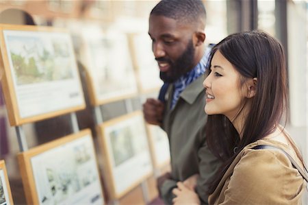 decision - Smiling young couple looking at real estate listings at storefront Stock Photo - Premium Royalty-Free, Code: 6113-09058573