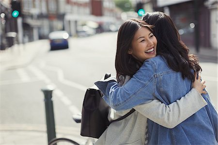Smiling affectionate female friends hugging on sunny urban street Stock Photo - Premium Royalty-Free, Code: 6113-09058511