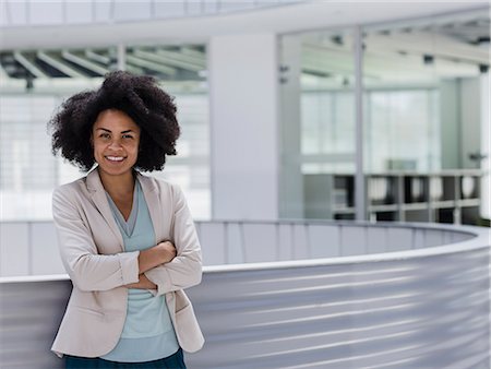 simsearch:6113-09058718,k - Portrait smiling confident businesswoman with arms crossed in office atrium Foto de stock - Royalty Free Premium, Número: 6113-09058649