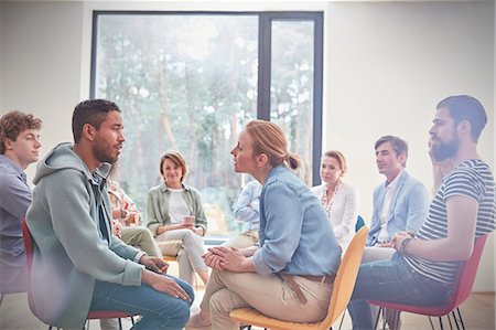 simsearch:6113-09058812,k - Group watching man and woman talking face to face in group therapy session Stock Photo - Premium Royalty-Free, Code: 6113-09058768