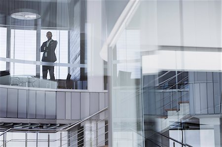 simsearch:6113-09058645,k - Confident CEO businessman standing with arms crossed at modern office window Photographie de stock - Premium Libres de Droits, Code: 6113-09058700