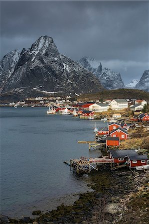 Fishing village at waterfront below rugged mountains, Reine, Lofoten, Norway Stock Photo - Premium Royalty-Free, Code: 6113-09058840