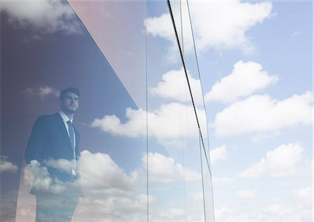 Businessman looking out modern office window at blue sky and clouds Foto de stock - Sin royalties Premium, Código: 6113-09058867