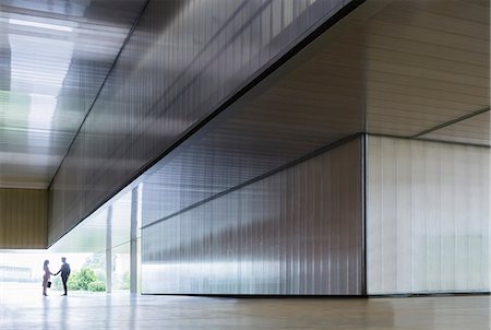 simsearch:6122-07701735,k - Silhouette businessman and businesswoman handshaking in modern office lobby corridor Foto de stock - Sin royalties Premium, Código: 6113-09058872