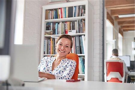 simsearch:6113-07565804,k - Portrait smiling, confident businesswoman working at laptop in office Stock Photo - Premium Royalty-Free, Code: 6113-09058985