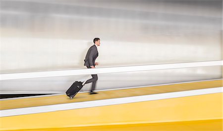 simsearch:628-05817505,k - Businessman running, pulling suitcase up airport ramp Photographie de stock - Premium Libres de Droits, Code: 6113-09058908