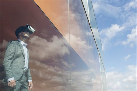 Businessman using virtual reality simulator glasses at modern window with cloud reflection Photographie de stock - Premium Libres de Droits, Code: 6113-09058909