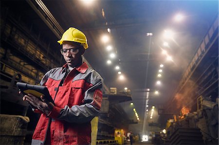 Steelworker using digital tablet in steel mill Stock Photo - Premium Royalty-Free, Code: 6113-09059044