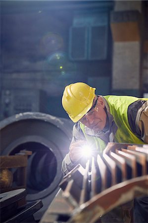 Focused steelworker with flashlight examining steel part in steel mill Foto de stock - Sin royalties Premium, Código: 6113-09059086