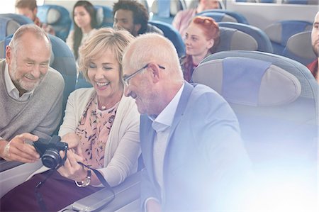 pasajero (hombre y mujer) - Smiling friends looking at photos on digital camera on airplane Foto de stock - Sin royalties Premium, Código: 6113-09059097