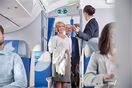 flight attendant walking - Flight attendant greeting passengers boarding airplane Stock Photo - Premium Royalty-Free, Code: 6113-09059141