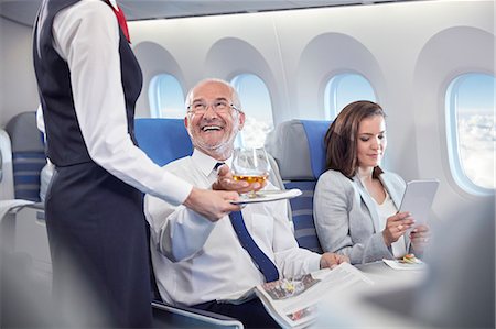 pasajero (hombre y mujer) - Flight attendant serving whiskey to smiling businessman riding in first class on airplane Foto de stock - Sin royalties Premium, Código: 6113-09059148