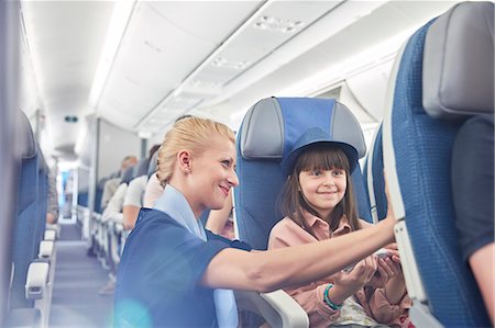 Flight attendant helping girl passenger on airplane Stock Photo - Premium Royalty-Free, Code: 6113-09059169