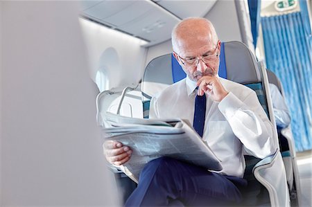 simsearch:6102-07843643,k - Businessman reading newspaper on airplane Photographie de stock - Premium Libres de Droits, Code: 6113-09059172