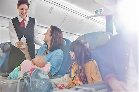 free images of men holding baby - Smiling flight attendant bringing baby bottle to mother with baby on airplane Stock Photo - Premium Royalty-Free, Code: 6113-09059184