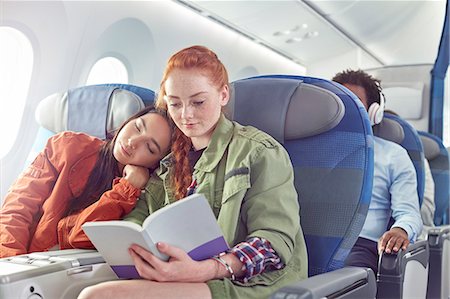 Affectionate young lesbian couple sleeping and reading on airplane Foto de stock - Sin royalties Premium, Código: 6113-09059186