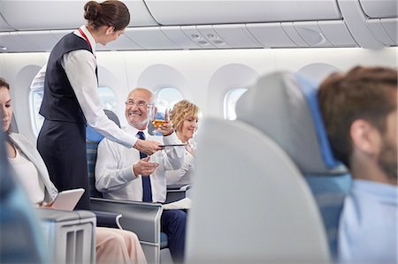 Flight attendant serving whiskey to businessman in first class on airplane Foto de stock - Sin royalties Premium, Código: 6113-09059196