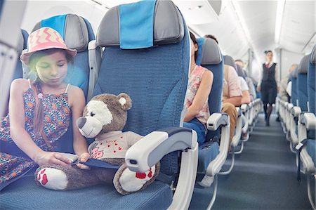 Girl fastening seat belt on stuffed animal on airplane Stock Photo - Premium Royalty-Free, Code: 6113-09059110